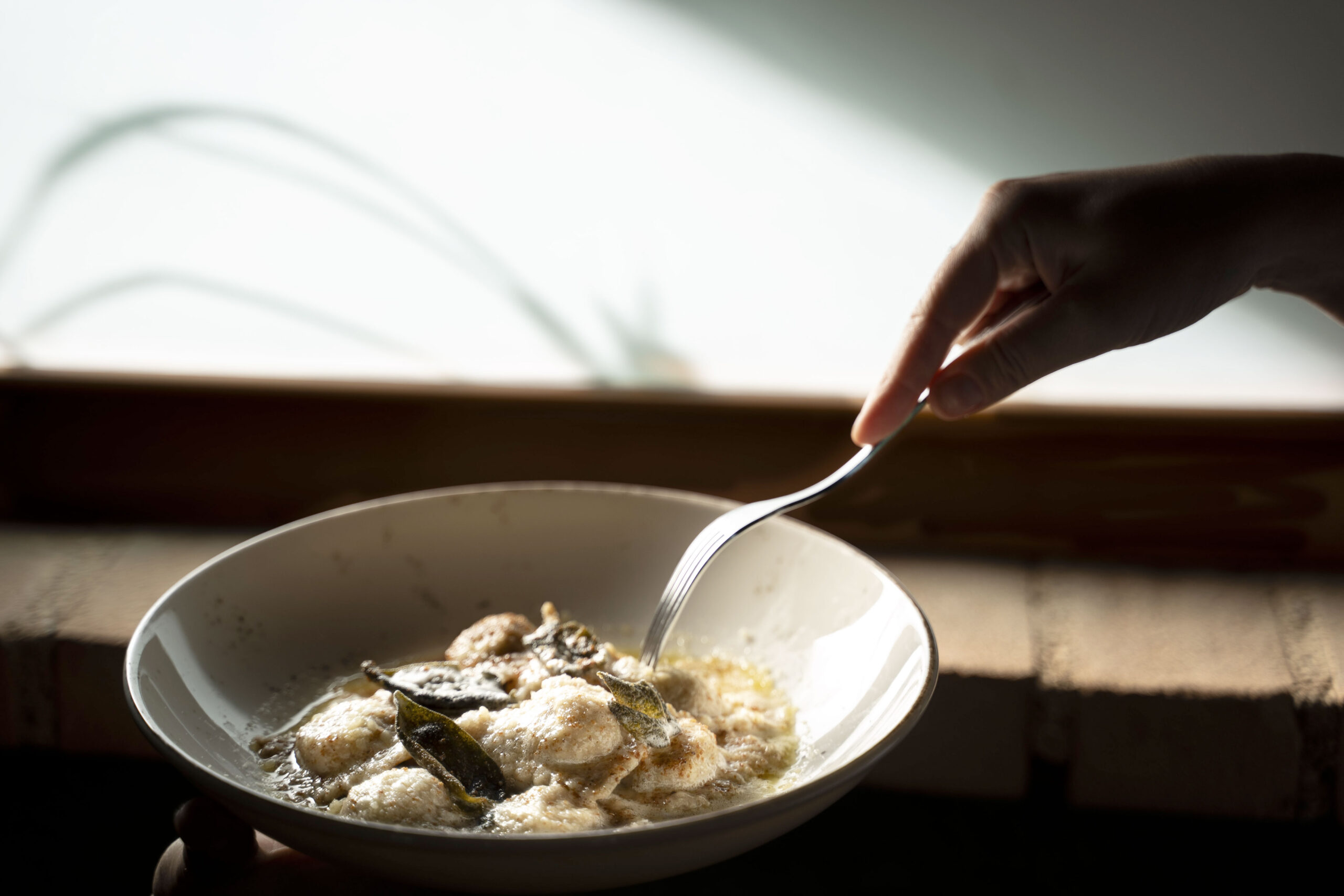 Questi ravioli fatti in casa sono un tripudio di sapori autentici, con un ripieno ricco di pane, formaggio, prezzemolo e aglio, che richiama le antiche ricette italiane. Conditi con burro nocciolino e foglie di salvia croccante.